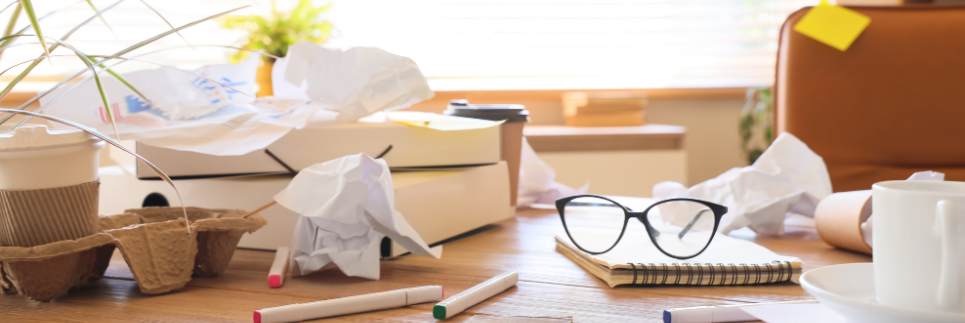 glasses atop a messy desk with crumbled papers and coffees