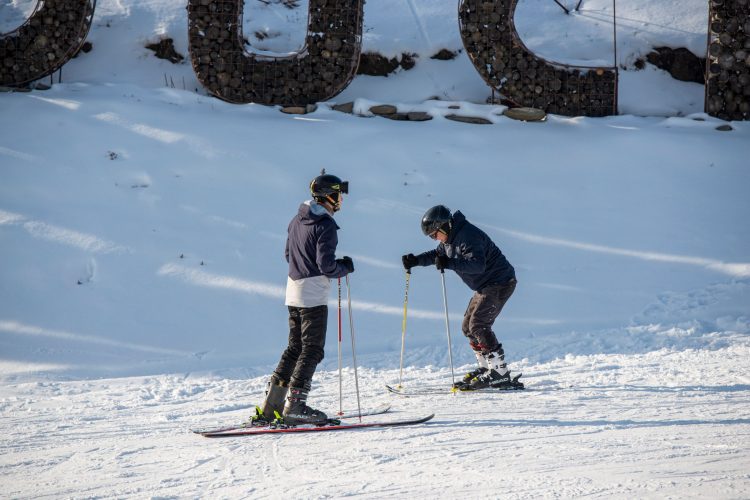 Two skiiers on a snowy path learning